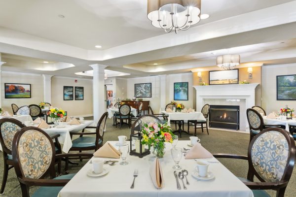 A formal dining room with several tables, chairs, and a fireplace