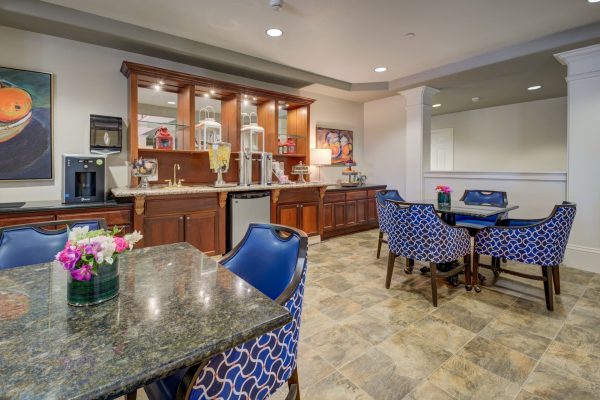 A dining area with tables, chairs, and a bar area at the back