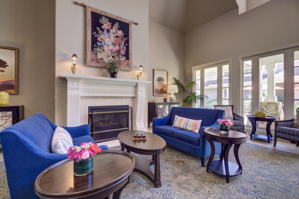 A seating area with blue couches, coffee tables, and a fireplace