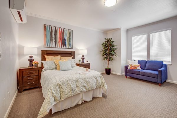 A bright and cozy bedroom with a bed, couch, and two nightstands