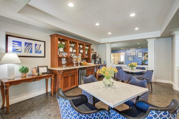 A seating area with tables, chairs, and a kitchenette