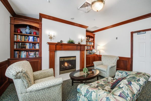 A small seating area with a couch, chairs, a coffee table, a fireplace, and a built-in bookshelf