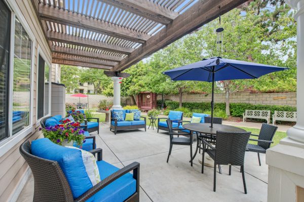 A covered outdoor seating area with blue cushions