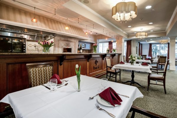 A formal dining area with tables, chairs, and a long bar