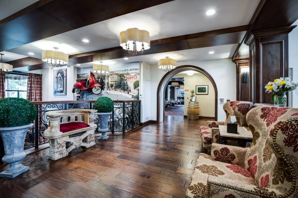 A hallway at the top of the stairs with armchairs to the right and an archway in the distance