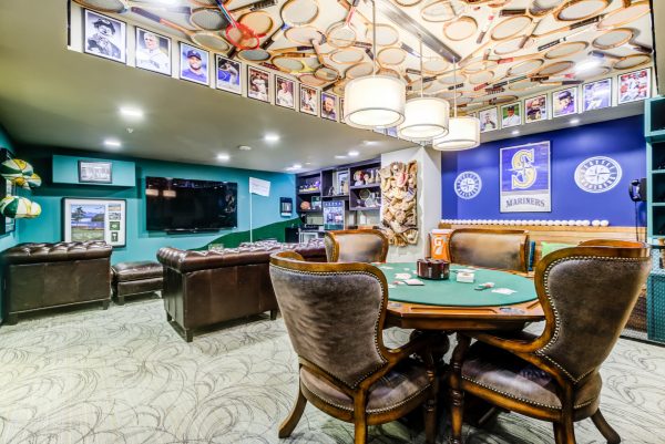 A sports-themed room with a card table, chairs, a couch, and a television