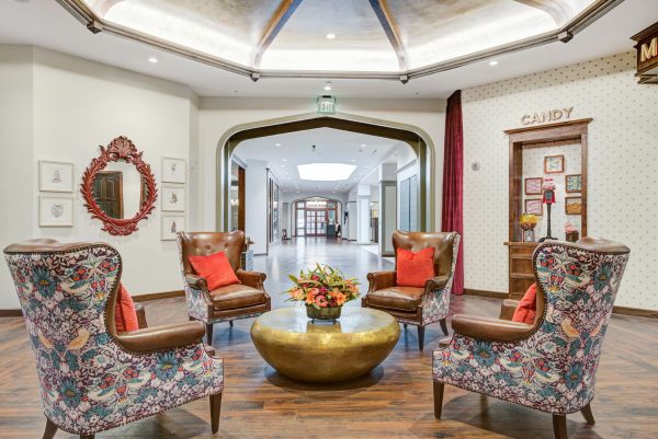 Four large armchairs around a gold coffee table with a long hallway in the background