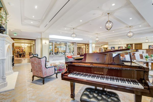 A large room with tables, chairs, and a piano