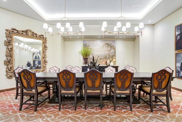 A large dining table with chairs and a large mirror in the background