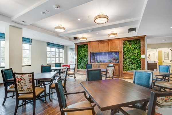 A communal area with tables, chairs, and an aquarium in the background