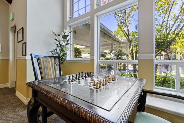 A chess table and chairs in front of a large window