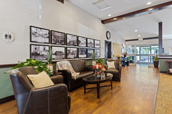 A seating area with brown couches, a coffee table, and photos on the wall in the background