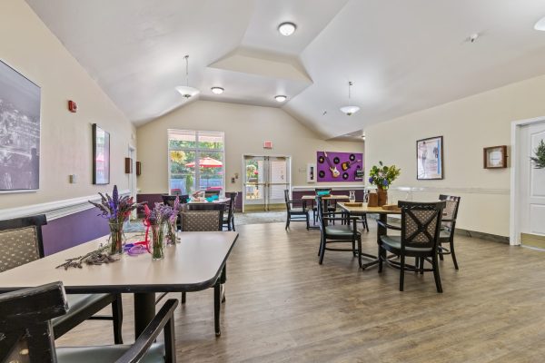 A multipurpose room with tables, chairs, and guitar and records on the wall in the background