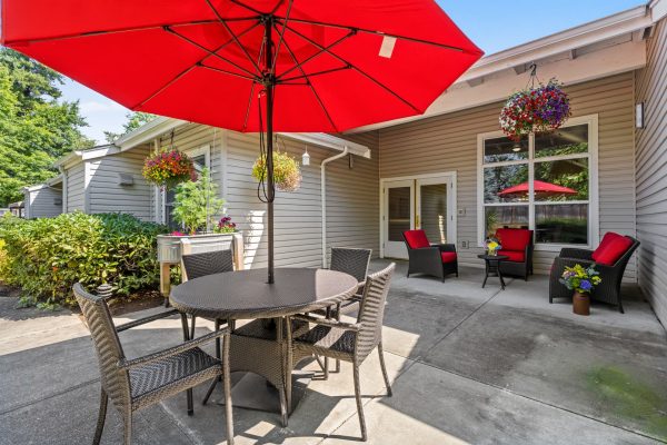 An outdoor patio set with four chairs and a red umbrella