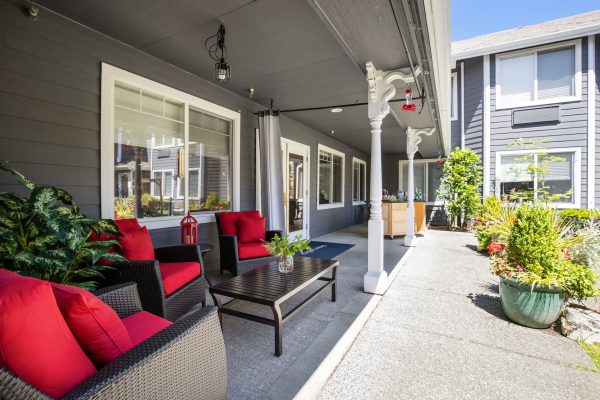 A covered outdoor seating area with a table and chairs that have red cushions