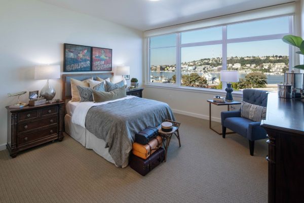 A bedroom with a large window, bed, nightstands, and dresser