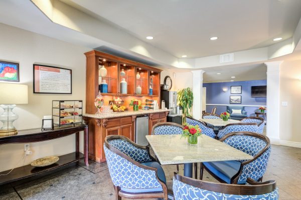 A small seating area with a table and four chairs and a kitchenette in the background