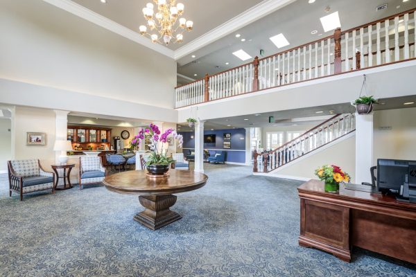 The lobby, featuring a desk with a computer, a large round table, and a staircase in the background