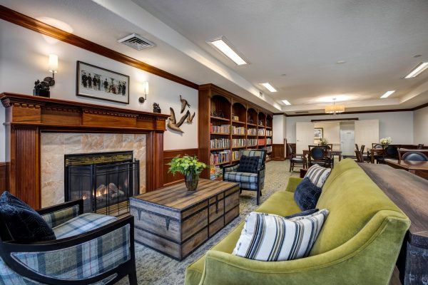 A large room with a green couch, two plaid armchairs, and a fireplace