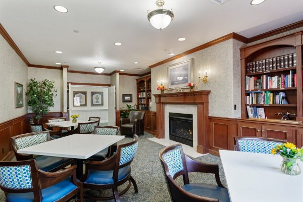 A cozy seating area with tables, chairs, and a fireplace