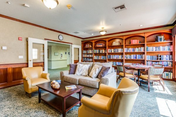 A library with a large built-in bookshelf, tables, and chairs