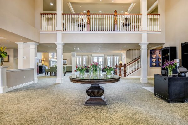 The large lobby, with a large round table in the middle and a staircase in the background