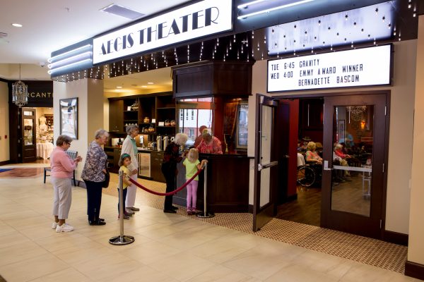 Residents and their grandchildren buying movie tickets at the Aegis Theater