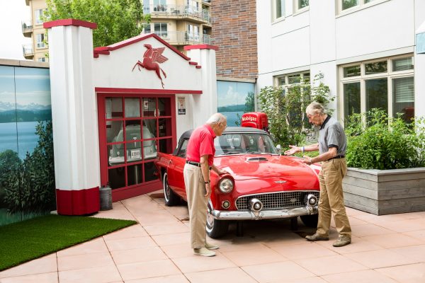 Two residents looking at an old red classic car