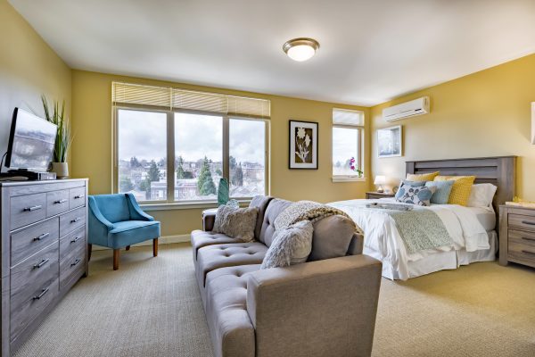 A bedroom with a large bed, couch, dresser, and television