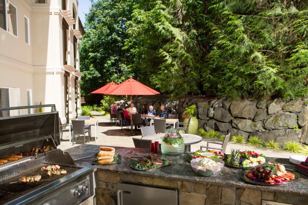 An outdoor eating area with a grill and food on a counter in the foreground