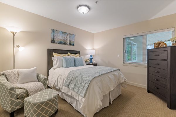 A bedroom with a bed, armchair, and dresser