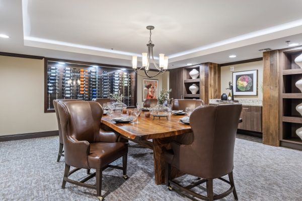 A dining room with a large table and chairs, and a wine rack in the background