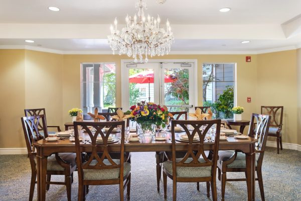 A large dining table and chairs with a chandelier hanging overhead