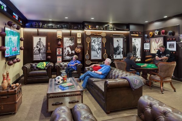 A sports-themed room with couches, tables, chairs, and televisions