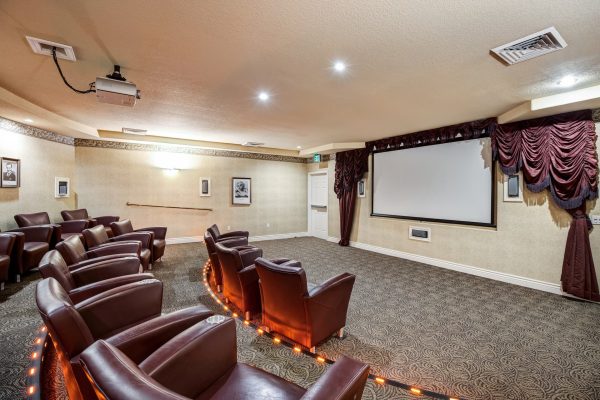 A movie theatre room with cozy armchairs and a large screen