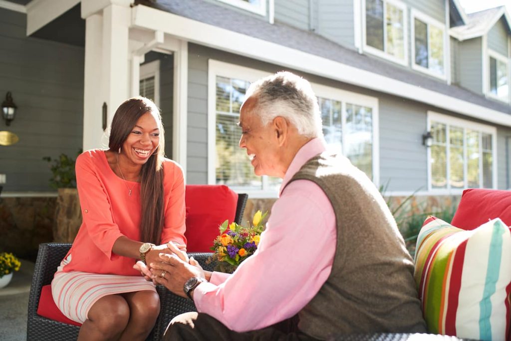 A resident sitting with his granddaughter and holding her hand