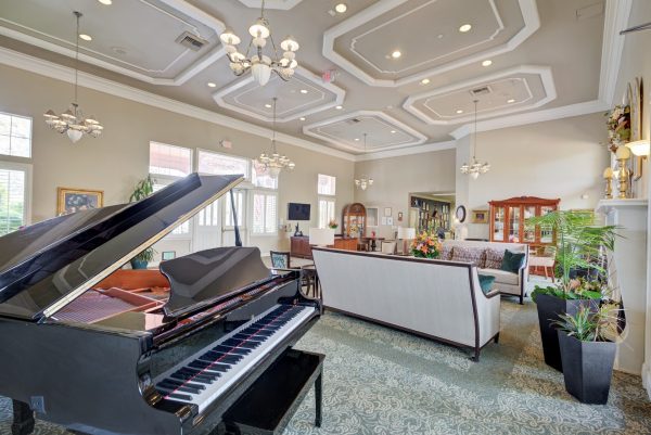 A bright, open room with large windows, white couches, and a black grand piano