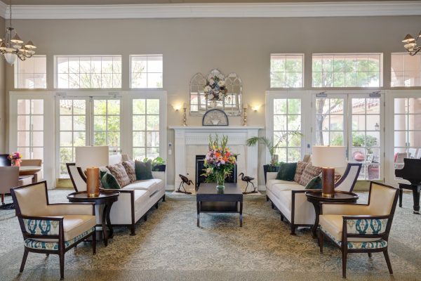 A bright, open room with large windows, white couches, beige chairs, and a fireplace