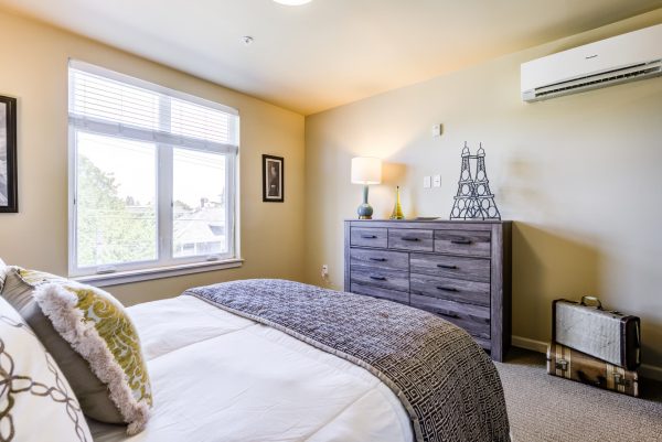 A bedroom with a cozy bed, dresser, and window