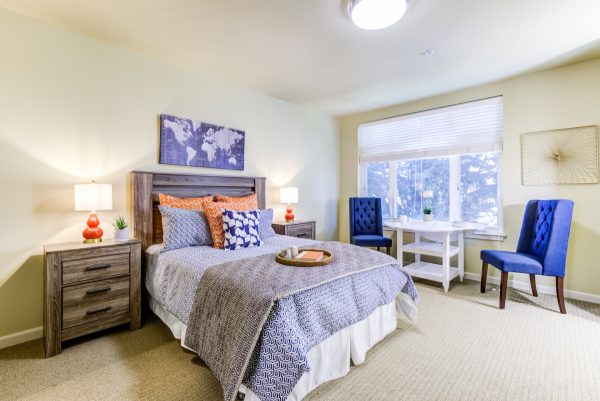 A bedroom with a cozy bed, table and chairs, and window