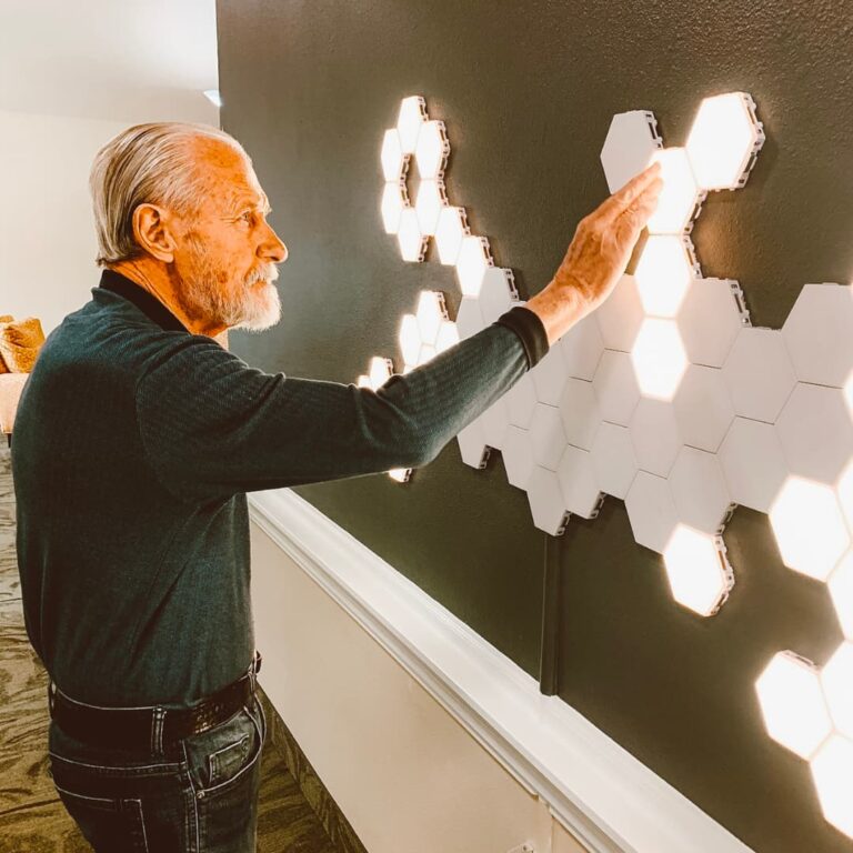 A resident touching a lit-up piece of art on the wall