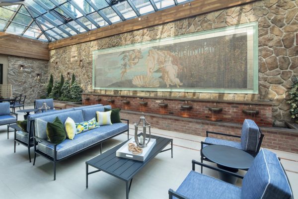 A large, covered seating area with a glass ceiling and large painting in the background