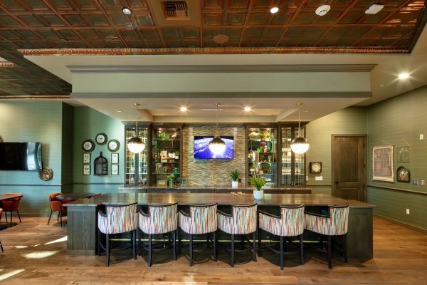 A large table colorful seats in a sage green room.