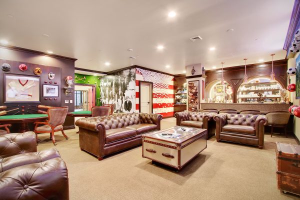 A sports-themed room with couches, tables, chairs, and televisions