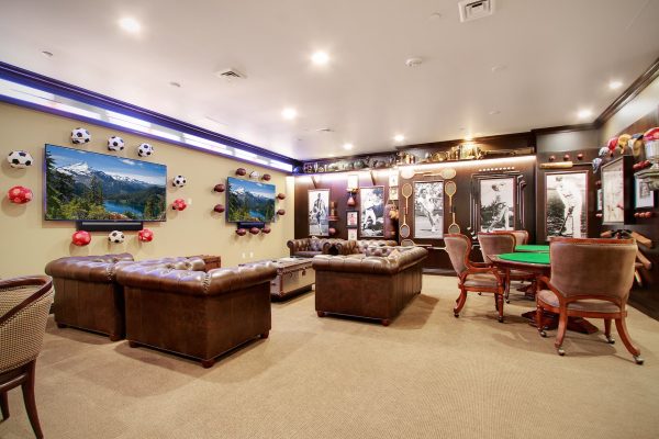 A sports-themed room with couches, tables, chairs, and televisions