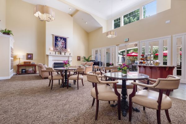 A large open seating area with tables, chairs, and a fireplace