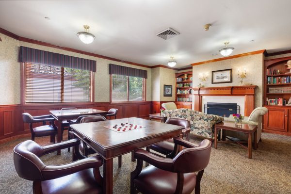 A game room with tables, chairs, and a fireplace