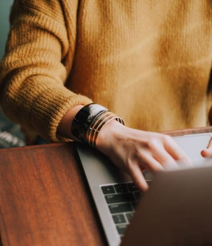 A woman ‘s hand typing on a laptop