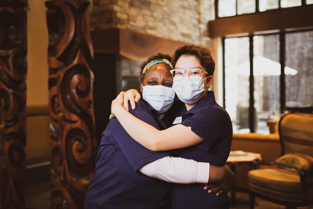 Two employees wearing masks and hugging