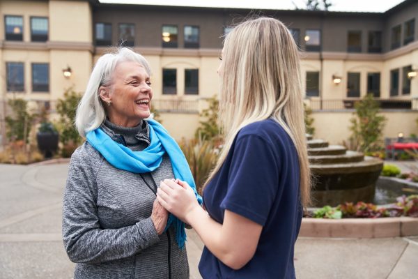 A resident and an employee holding hands outside